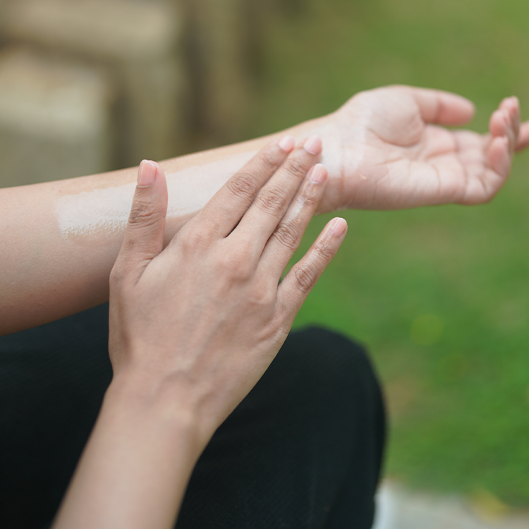 A hand smoothing oil into the back of the other hand